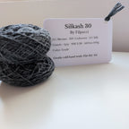 Ball of gray yarn with a label on a white surface