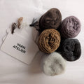 Yarn balls in various colors with a 'Yarn Atelier' sign on a light background